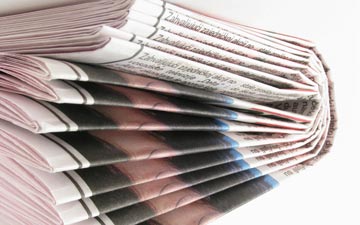 Folded newspapers stacked in a pile.